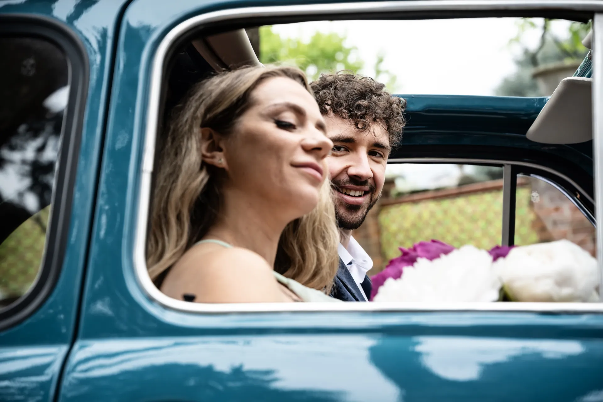 Sposi abbracciati nell'auto d'epoca con il bouquet, scatto realizzato durante il workshop di wedding photography