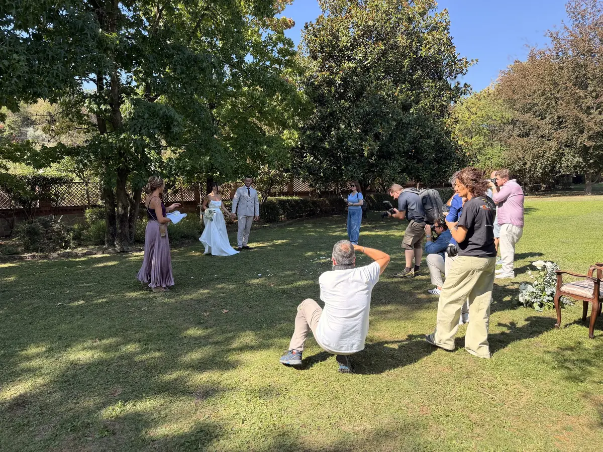 Corsisti fotografano sposi e damigella sul prato del parco di Villa Garnerone