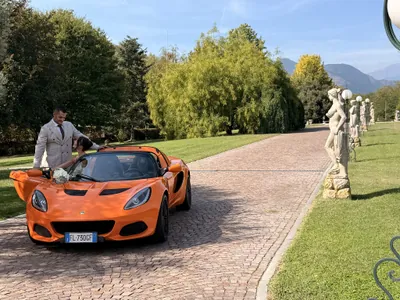 Lo sposo apre la portiera della Lotus Elise alla sposa nel viale alberato